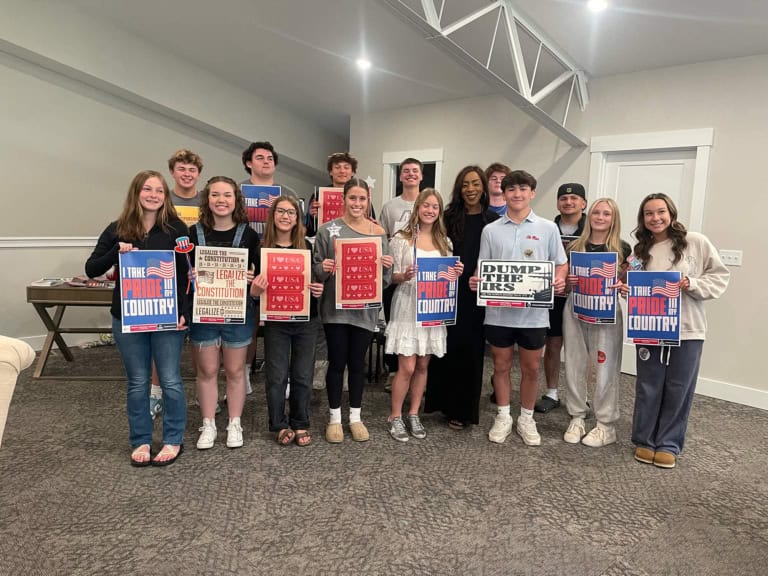 Young people holding patriotic and political signs promoting pride in the USA and supporting constitutional rights.