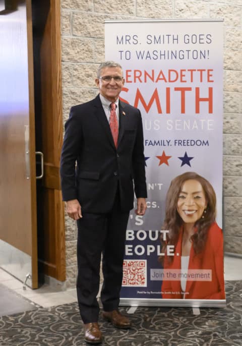 Bernadette Smith standing next to campaign poster for U.S. Senate race.