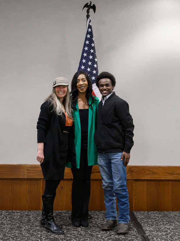 Bernadette Smith with supporters at campaign event in front of U.S. flag.