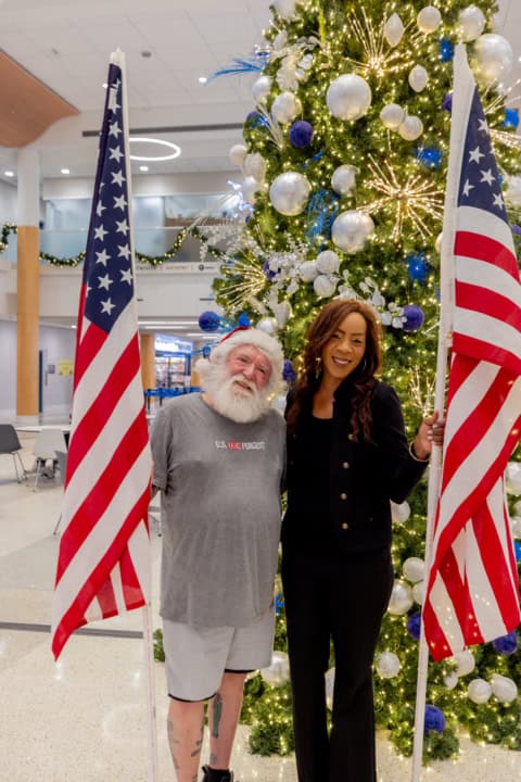 Bernadette Smith holding American flags at holiday event with Santa.